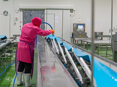 A person spraying down a conveyor parts in a wet condition